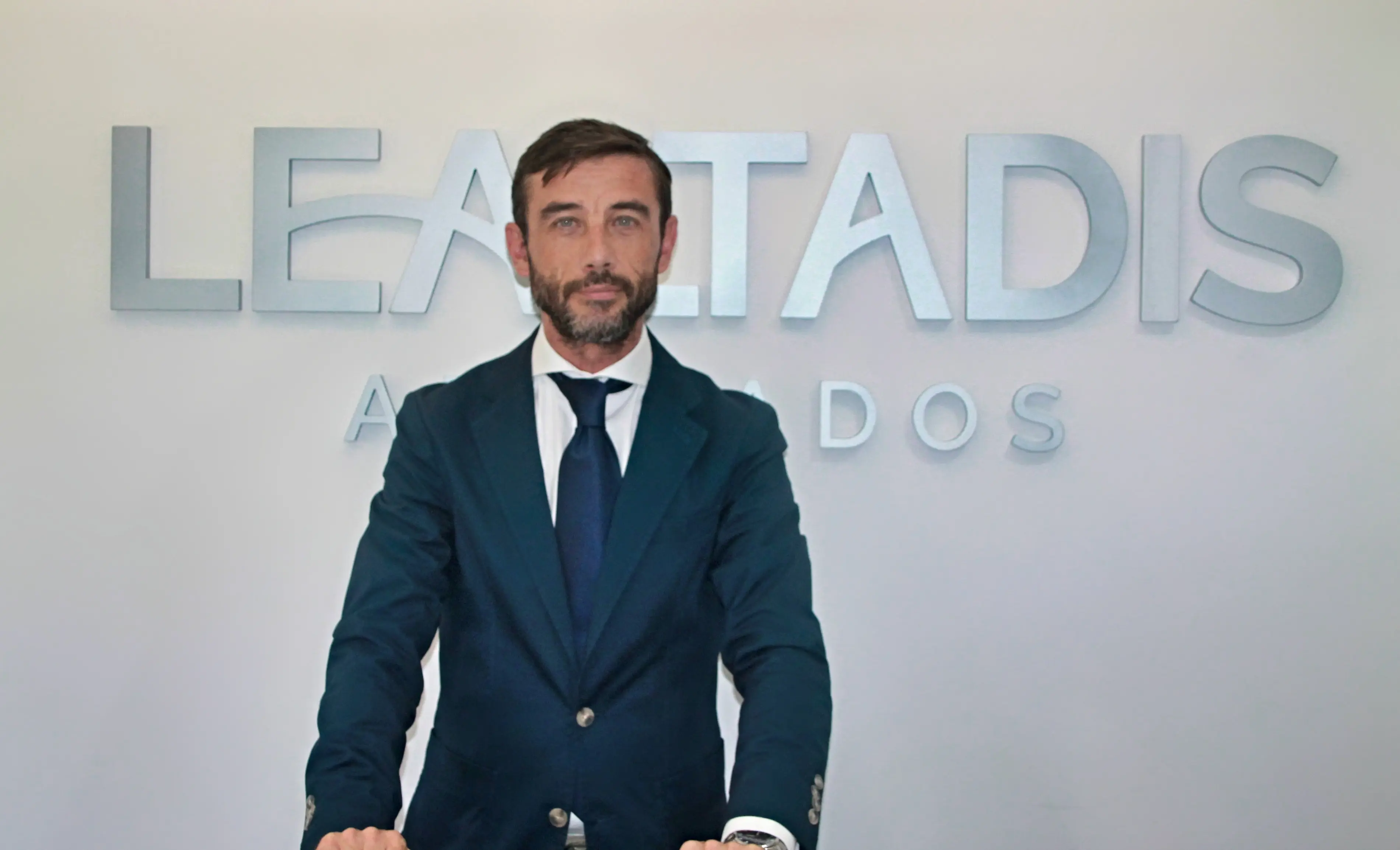 Retrato profesional de uno de los abogados de Lealtadis frente al logo del despacho.